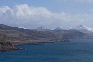 Snow capped mountains in the background and a sea loch in the foreground