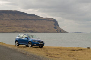 Photo of a car beside a sea loch on the Isle of Mull. Large cliffs in the background