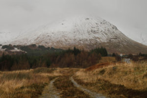 Snow capped mountain on the isle of mull. A vehicle track down the centre of the photo going off in to the distance