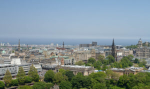 Roof tops across Edinburgh city. Blue sky, tree tops, tall spires