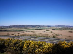 Photo of ploughed fields and running left to right across the images is an empty motorway